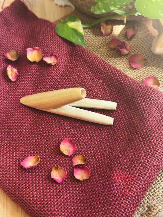 double nostril kuripe on a textured red fabric with pink flower petals and green leaves.