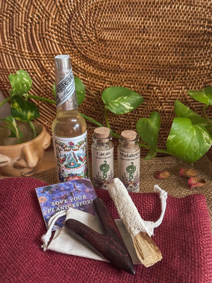 Bottles, tools, and a card on a woven surface with plants in the background